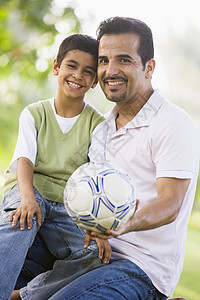 父亲和儿子在户外公园里拥抱和微笑后代中年孩子们男士身份幸福情感爸爸们家长小学生图片