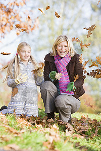 在公园户外露天玩叶子和微笑的女子和少女情感小学生妈妈们幸福落叶花园人种外表小学女儿们图片