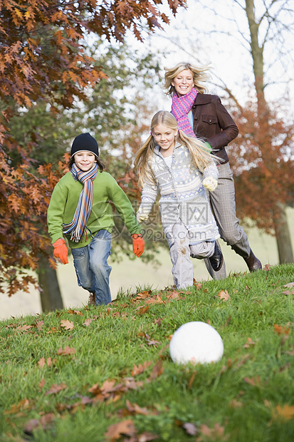 户外母亲与两名幼儿一起在公园里玩足球和微笑图片