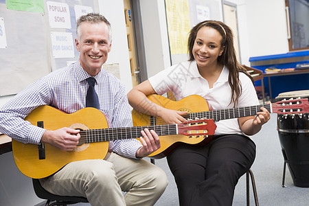 接受课堂老师吉他课的女学生在课堂上从教师那里学吉他黑发婴儿教室成年人吉他手成人外表班级一代原声图片
