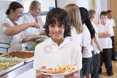 餐厅线上的学生 其中一人拿着健康饮食 看照相机深入田间谷物男孩们男生服务员工人围裙同学孩子们美食同学们图片