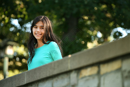 年轻女孩站在桥上的桥上混血孩子石头晴天混血儿壁架背景图片