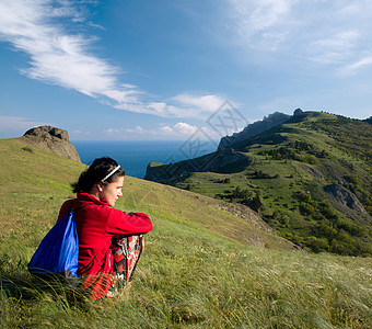 女孩坐在海边的山上图片