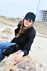 女孩坐在日志上天空套衫木头海洋光束女士海滩木材女性快乐图片