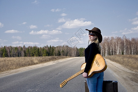 有吉他的国家女孩 独自在路上走假期天空靴子头发旅行游客运输女性汽车身体图片