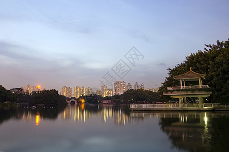 夜间在湖边公园池塘反射建筑物树木发光夜景亭子图片