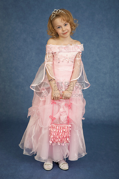 穿粉红裙子的小女孩站在蓝色背景上图片