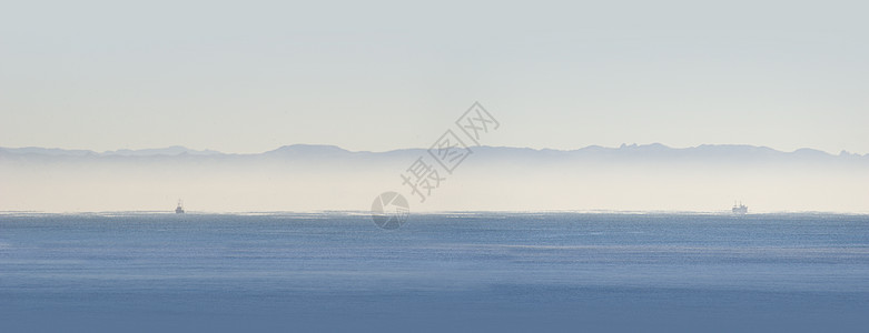 两艘渔船全景海洋海岸丘陵天空薄雾图片