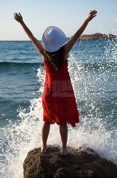 美丽的女孩在海浪中飘荡幸福飞溅女性假期享受自由帽子海滩乐趣太阳图片