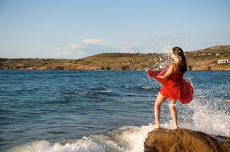 美丽的女孩在海浪中飘荡自由女性享受乐趣帽子幸福裙子海滩太阳假期图片