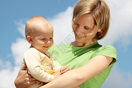 母亲在蓝天下怀着婴儿幸福男生儿子孩子母性闲暇蓝色家庭天空父母图片