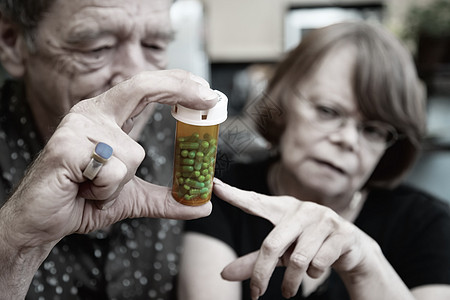 家中有处方的老年夫妇药品胶囊瓶子丈夫姿势药物戒指男性眼镜女士背景