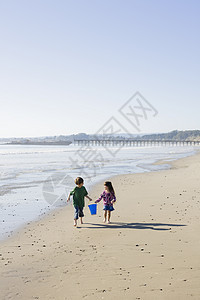 海滩儿童波浪享受孩子兄弟姐妹海洋友谊童年姐姐青少年天空图片