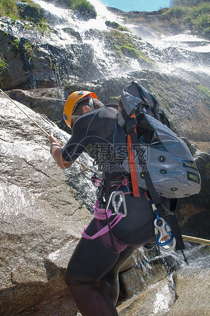 男人在瀑布下游假期冒险绳索行动峡谷头盔悬崖男士地形保安图片