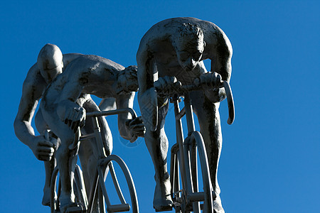 三个在斜坡上的骑自行车的人齿轮鞠躬天空蓝色运动轮子胜利戏剧性跑步雕塑图片