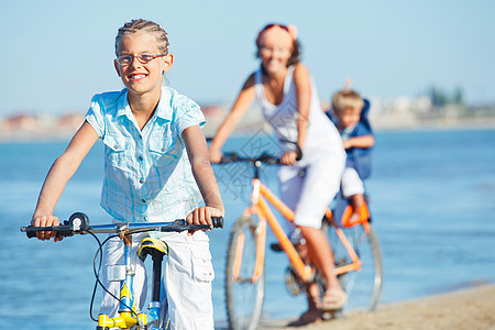 可爱的女孩和她的母亲和兄弟一起骑自行车波浪女士微笑儿子娱乐运动女性孩子金发男生图片