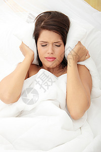 女性用枕头闭上耳朵卧室挫折沮丧女士黑发疾病就寝噪音压力苏醒图片