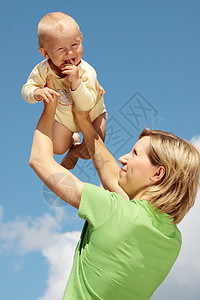 母亲在蓝天下怀着婴儿微笑童年孩子男生家庭母性公园乐趣闲暇女性图片