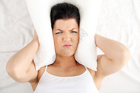 女人躺在床上 用枕头闭着耳朵苏醒失眠压力挫折女孩噪音黑发女性女士疾病图片