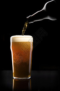 啤酒倒入玻璃杯中气泡酒精啤酒瓶泡沫啤酒杯酒吧酿造图片