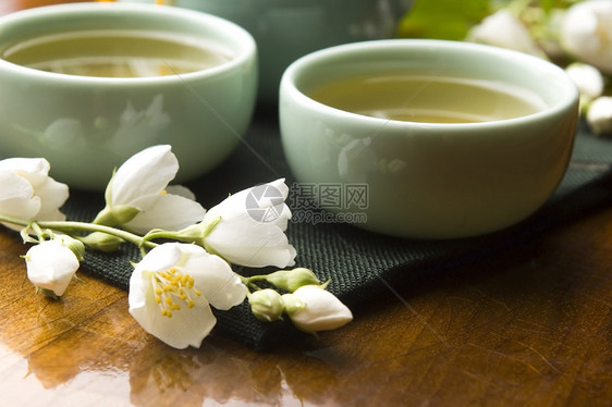 茶壶和茶壶中的青茶 杯子上含茉米 木制餐桌茉莉陶瓷茉莉花花园制品香气球座饮料生活叶子图片