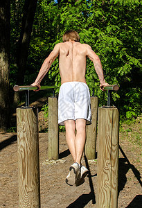 男人在森林的酒吧里拉起拖力 从后面重量男性训练健美手臂肌肉成就运动员力量运动图片