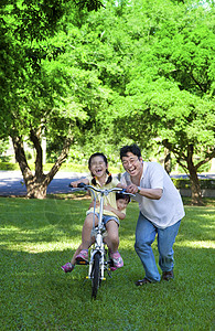 父亲教两个小女孩骑自行车去上学图片