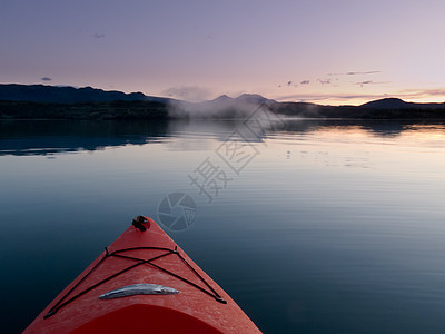 通过宁静的日落水域 在一条皮艇上划过平静的夕阳水域图片