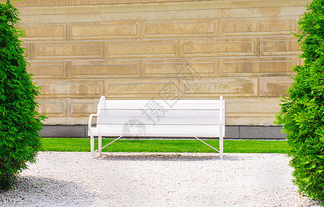 阳光明媚的一天 墙壁背景上的空长椅图片