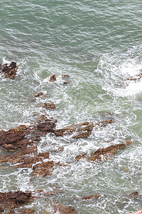 热带海滩上的石头海岸线太阳支撑异国卵石岩石旅行海浪碎石地平线图片