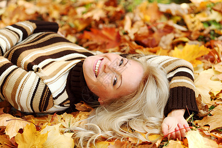 秋叶中的妇女脚尖微笑眼睛毛衣幸福团体女士季节女性金发女郎叶子图片