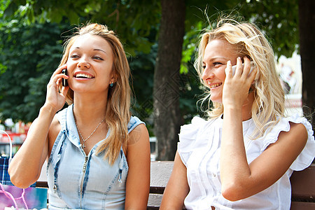 两个在电话上说话的年轻女孩金发女郎长椅魅力青年温暖姐妹公园喜悦眼睛友谊图片