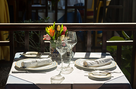 阳光下外边餐厅的餐桌设置银器桌布咖啡店假期海滩午餐桌子花朵刀具餐巾纸图片