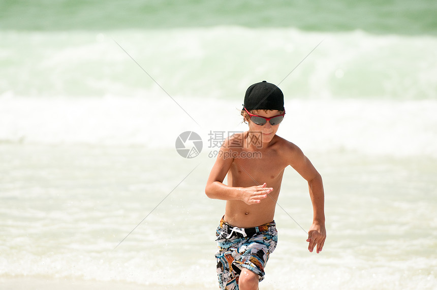 年青男孩在大洋中奔跑旅行赤脚海洋日落幸福孩子太阳镜健身快乐运动图片