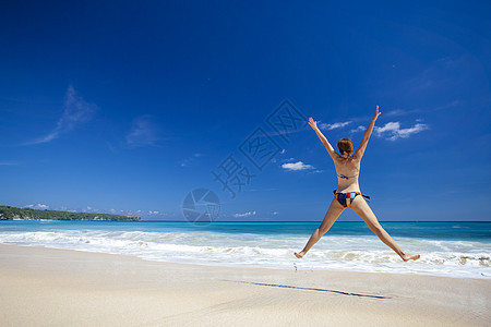 女人在海滩上跳跃热带身体蓝色女孩棕褐色海洋成功乐趣太阳自由图片