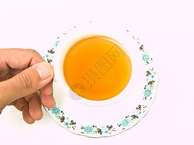 用手握着的茶杯 用花纹 将它与Whit隔离开来玻璃饮料盘子花朵白色草本早餐液体棕色杯子图片