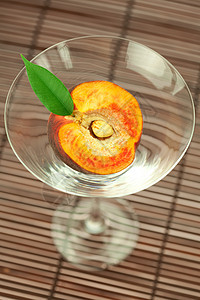 玛蒂尼酒杯中的桃子 在竹垫上红色橙子条纹曲线阴影黄色棕色水果圆圈玻璃图片