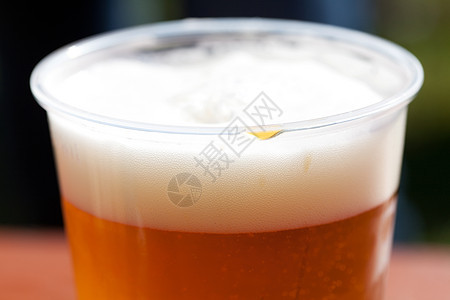 桌上的轻啤酒杯玻璃阳光液体庆典泡沫金子花园酒吧托盘木头图片
