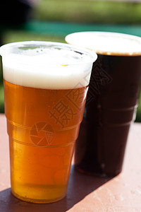 桌子上闪光和黑啤酒的玻璃杯餐厅泡沫玻璃金子庆典啤酒派对木头酒精花园图片