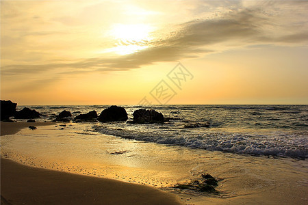 海中金色的日落假期金子海洋岩石天空太阳海浪地平线阳光反射图片