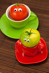 竹垫上杯子里有眼睛的西红柿菜肴陶瓷用具木头飞碟早餐创造力蔬菜笑脸食物背景图片