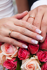 新娘和新郎的手与戒指 在花束上图片