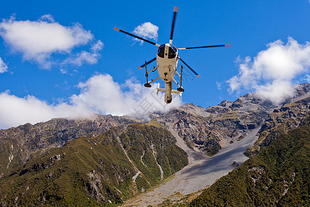 救援直升机飞越山地荒野上空图片