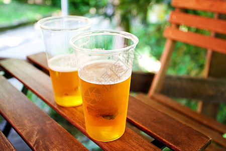 站在木制桌上的啤酒杯餐厅金子花园阳光酒吧木头琥珀色托盘液体庆典图片