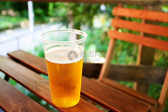 站在木制桌上的啤酒杯泡沫酒吧木头液体阳光啤酒琥珀色花园餐厅托盘图片