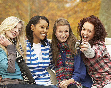 摄像头拍摄的四位青少年女孩组O组树叶笑声公园混血微笑朋友们叶子座位长椅女性图片