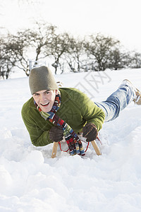 年青男子在雪地风景中的滑雪上骑车围巾下雪农村帽子手套季节寒冷雪橇笑声微笑图片