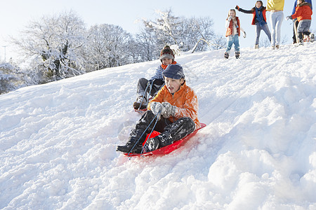 带着家庭守望的年轻男孩滑雪下山四个人母亲男性场景场地父亲雪橇女孩女性女士背景