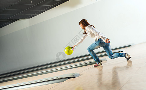 可爱的年轻女子扔了一个保龄球娱乐游戏投掷闲暇女性乐趣车道蓝色投球胡同图片