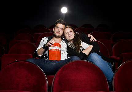 电影院的年轻夫妇女性愚昧爆米花男士快乐乐趣观众夜生活夫妻观众席背景图片
